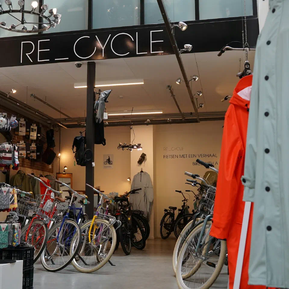 L'intérieur d'un magasin de vélos d'occasion, avec des vélos de ville alignés au fond.